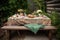 picnic table with a blanket, dishes, and silverware set out for an elegant outdoor meal