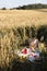 Picnic in the wheat field with basket, summer hat, lemonade, bread and fruits