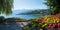 Pictorial lakeside promenade Faulensee, with bench and colorful flowers, view to lake Thunersee and swiss alps