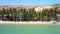 Pictorial view sand beach lined by palms at hills