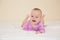 Picture of adorable baby in violet bodysuit lying on bed