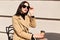 Picture of adorable stylish young cute female touching her black sunglasses with fingers, enjoying sunny day outdoors, holding