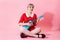 Picture of beautiful dollish girl with short light violet hair wearing red dress playing blue ukulele over pink