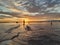 Picture of a beautiful sunset with the silhouette of a fisher man on a flooded jetty. Vacation background.