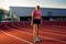 Picture of beautiful young European female runner or sprinter standing on outdoor stadium track, feeling exhausted after