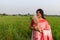 A picture of a Bengali girl wearing a red and white sari in a vast paddy field in autumn