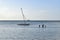 Picture of calm waters with a small sailing boat and a fisherman in action. Tranquility, scenic, relaxing.