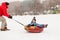 Picture of cheerful father skating son on tubing in winter afternoon
