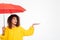 Picture of confused african woman in raincoat hiding under umbrella