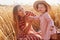 Picture of cute little child wearing pink smart dress, straw hat, smiling sincerely, spending time with her mother. Sweet cute mom
