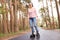 Picture of delighted glad good looking young woman rollerskating alone, being in middle of forest road, listening to music,