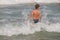 Picture of exciting boy running on beach beside waves. image of kid in evening sunlights on seaside background.