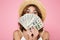 Picture of exited young brunette woman in straw hat covering face with money