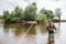 A picture of fisherman stands in shallow and looking straight forward. He has fly-fishing in hand. A spoon is shown on