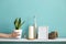 Picture frame mockup. White shelf against pastel turquoise wall with Candle and rocks in bottle. Hand