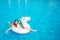 A picture of girl lying on air mattress and touching water in swimming pool with her hand. She has a lot of fun. Girl