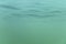 Picture of green to blue shades of water mass from under water. Fine structure of waves from below. Light green to mint color