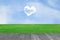 Picture of a heart cloud on blue sky in green field and wood plant