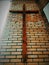 Picture of a large wooden Christian Protestant cross hanging on a brick wall of a Baptist church in perspective view