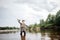 A picture of man holding up fly rod in right hand. He is standing in shallow water and looking straight. He is ready to