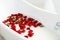 Picture of many red roses in bathroom filled with milk. Healthca