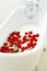 Picture of many red roses in bathroom filled with milk. Healthca