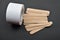 Picture of many wooden spatulas and roll of paper for wax depilation on black background