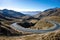 picture of mountain range, with winding road and clear blue sky in the background