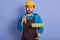 Picture portrait of sleepy tired construction worker closing his eyes, holding thermo mug and roller in both hands, wearing brown