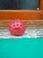 Picture of a red colored rubber ball shaped like a Corona virus on concrete surface