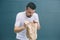 A picture of sick man trying to vomit in paper bag. He feels horrible. Isolated on striped and blue background.