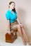 Picture of sitting on the sewing machine box charming young woman pinup girl in skirt and blue shirt having fun