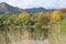 A picture of a stunning autumnal landascape with lots of colors, trees and a romantic lake surrounded by high mountains