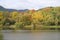 A picture of a stunning autumnal landascape with lots of colors, trees and a romantic lake surrounded by high mountains