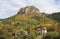 A picture of a stunning autumnal landascape with lots of colors and trees surrounded by high mountains