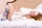 Picture of sweet glamor young blond woman relaxing lying on her back in white bed in a sweater and socks