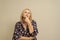 Picture of thoughtful contemplative caucasian woman wearing black dress on beige background keeps hand under chin