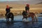 Picture of two horseriders in a river surrounded by a deserted valley under a blue sky