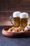 Picture of two mugs of beer and hot dogs on wooden tray