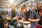 Picture of two young men sitting and having beat on drums. They are in room full of electric guitars. Guys play together.