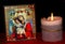 Picture of virgin Mary and little Jesus next to the candle on the red surface