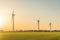 Picture of wind farm generators in the green field close to the road with cars at the sunset