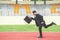 Picture of young businessman holding a briefcase and sprinting on the lanes of a track, Competition concept