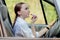 Picture of young businesswoman doing makeup while driving a car in the traffic jam