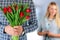 Picture of young man surprising woman with flowers.