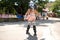 Picture of young roller skater outside skating alone. Professional baby in skating equipment have fun riding. Sunshine