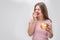 Picture of young woman bite piece of apple. She looks on camera. Another apple is on hand. Isolated on grey background.
