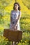 Picture of young woman in daisy filed with retro suitcase retro