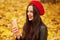 Picture of young woman making selfie or having video call in autumn park. Beautiful girl dresses redberet and leather jacket takes
