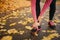 Picture of young woman stands on road and hold hands on feet. She feels pain. Woman suffer. She is alone in park.